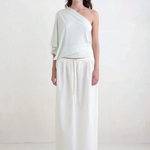 Model wearing KABE SHOP INC Rhea maxi skirt in white with an adjustable drawstring waistband and clean silhouette