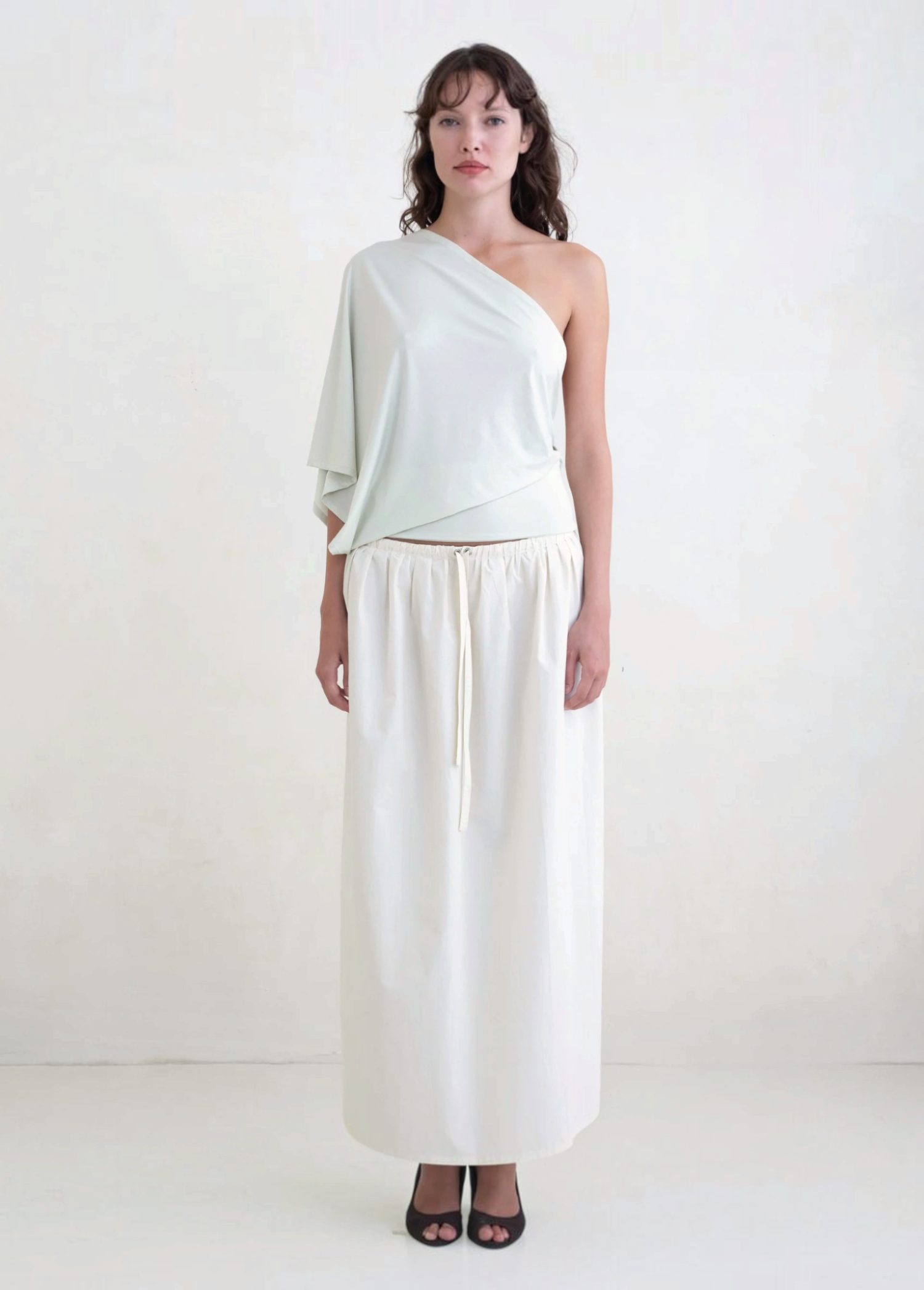 Model wearing KABE SHOP INC Rhea maxi skirt in white with an adjustable drawstring waistband and clean silhouette