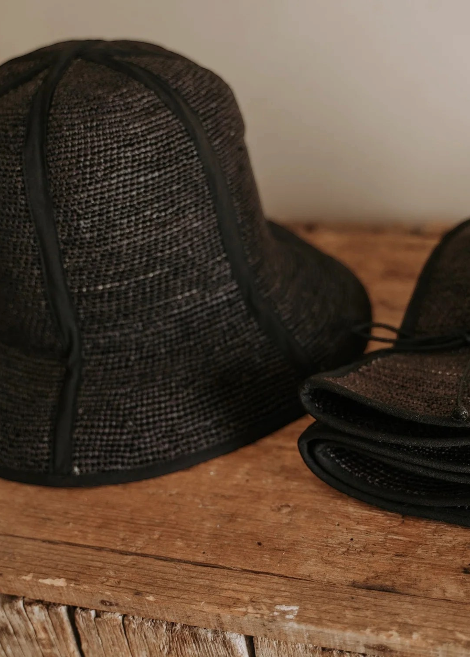 KABE SHOP INC Sandra foldable black straw hat with a classic silhouette, shown open and folded on a wooden surface.
