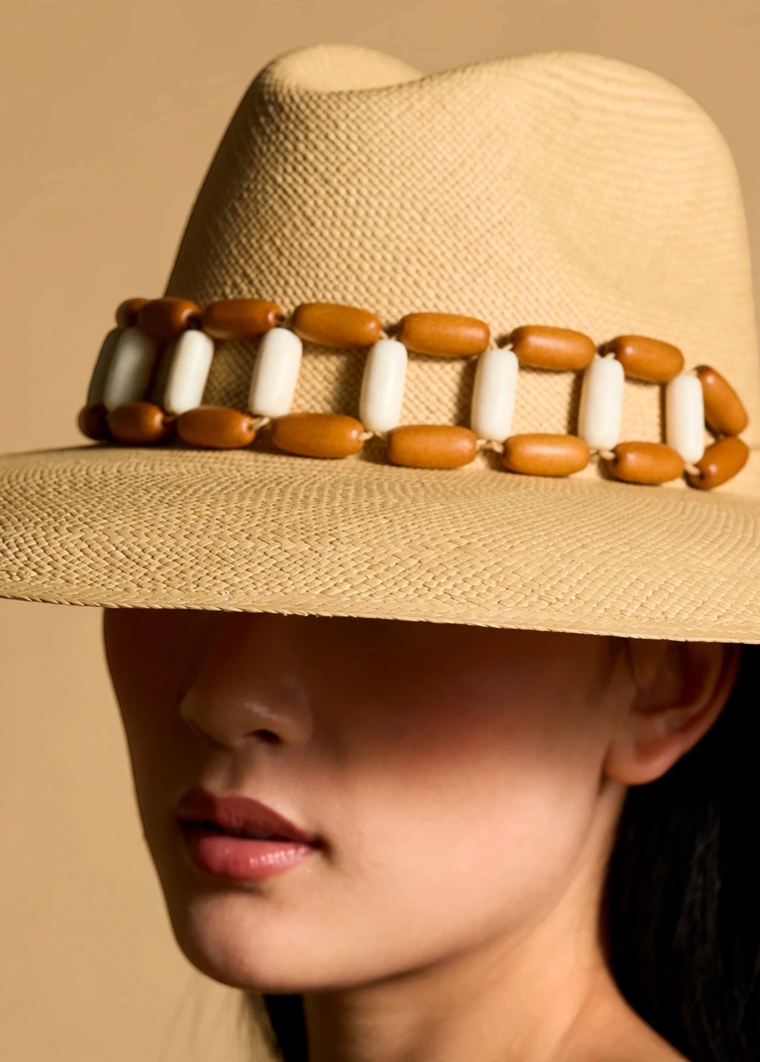 KABE SHOP INC Sine wide brim straw hat in beige with a decorative brown and white beaded band on a model