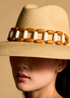 KABE SHOP INC Sine wide brim straw hat in beige with a decorative brown and white beaded band on a model