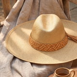 KABE SHOP INC Tucan wide brim straw hat with a woven leather band and tassel detail resting on a linen cloth.