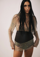 KABE SHOP INC Undone Corset Belt in black calfskin worn by a model over a shimmering metallic mesh dress