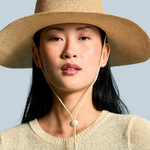 Model wearing a KABE SHOP INC Vitoria wide brim straw hat with a chin strap against a blue background