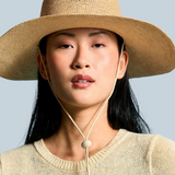 Model wearing a KABE SHOP INC Vitoria wide brim straw hat with a chin strap against a blue background