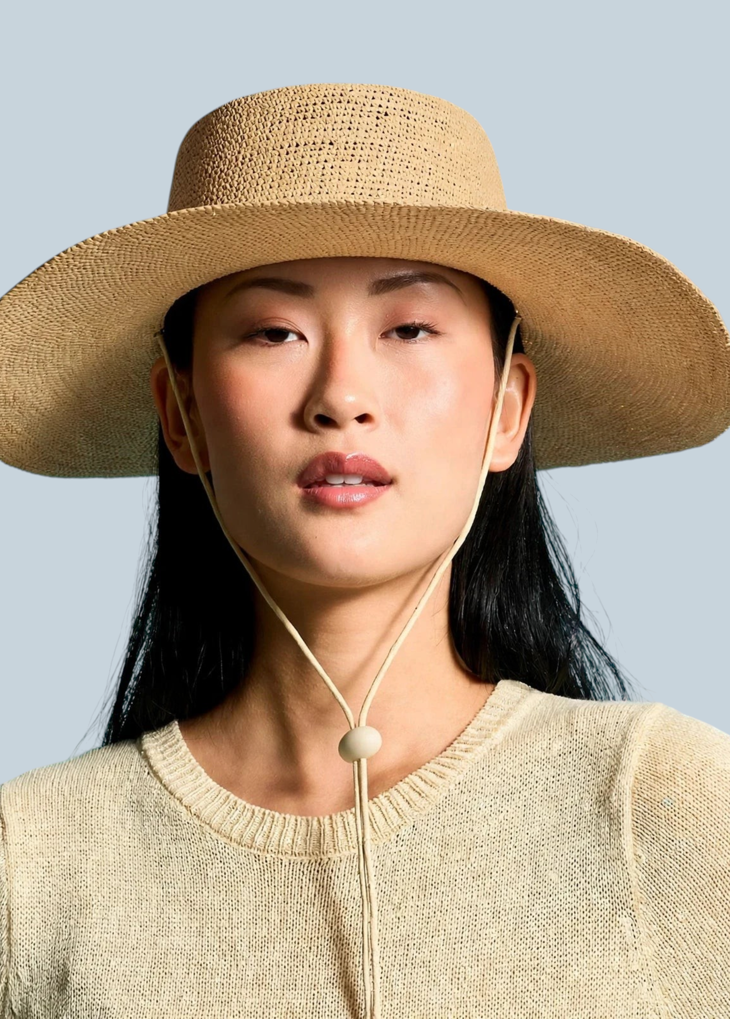 Model wearing a KABE SHOP INC Vitoria wide brim straw hat with a chin strap against a blue background