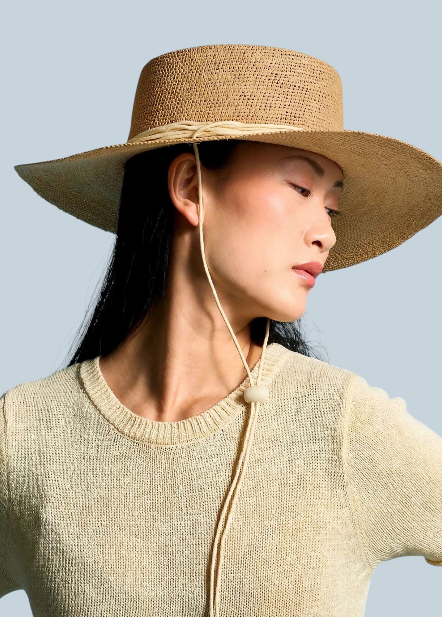 Model wearing a KABE SHOP INC Vitoria wide brim straw hat with a chin strap against a blue background