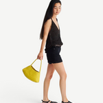 Model carrying a yellow handwoven Buffalo leather Rosanna Bag from KABE SHOP INC, featuring a sleek shoulder design.