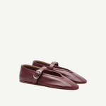 A pair of Stella Slipper Leather Shoes in rouge leather, featuring a strap with a polished buckle and a split front design, displayed against a plain white background.