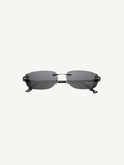 Paris sunglasses feature a rimless rectangle design with dark gray lenses and thin black arms, displayed against a plain white background. Inspired by iconic 2000s style, Paris offers reliable UV protection for everyday wear.