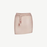 The Lumiere Skirt is a pale pink textured mini skirt featuring a matching waist tie with three round beads on each end and delicate sequin bead accents, shown against a plain white background.