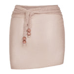 The Lumiere Skirt is a pale pink textured mini skirt featuring a matching waist tie with three round beads on each end and delicate sequin bead accents, shown against a plain white background.