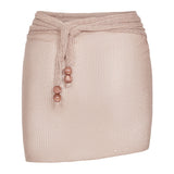The Lumiere Skirt is a pale pink textured mini skirt featuring a matching waist tie with three round beads on each end and delicate sequin bead accents, shown against a plain white background.