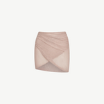 The Lumiere Skirt is a light pink, textured knit mini skirt with a criss-cross, wrap-style front and subtle sparkle details, featuring sequin bead accents for added shimmer, isolated on a white background.