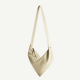 Introducing the Vancouver Sling Bag: a minimalist cream-colored sculptural shoulder bag with a single long strap, crafted from smooth, soft nappa leather and showcasing a subtle angled design, photographed on a plain white background.
