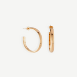 A pair of Irina Hoops 1.25″ featuring a shiny 14kt gold plate are displayed against a white background, with one earring shown front-facing and the other from the side to highlight their classic pierced back design.