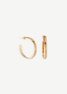 A pair of Irina Hoops 1.25″ featuring a shiny 14kt gold plate are displayed against a white background, with one earring shown front-facing and the other from the side to highlight their classic pierced back design.