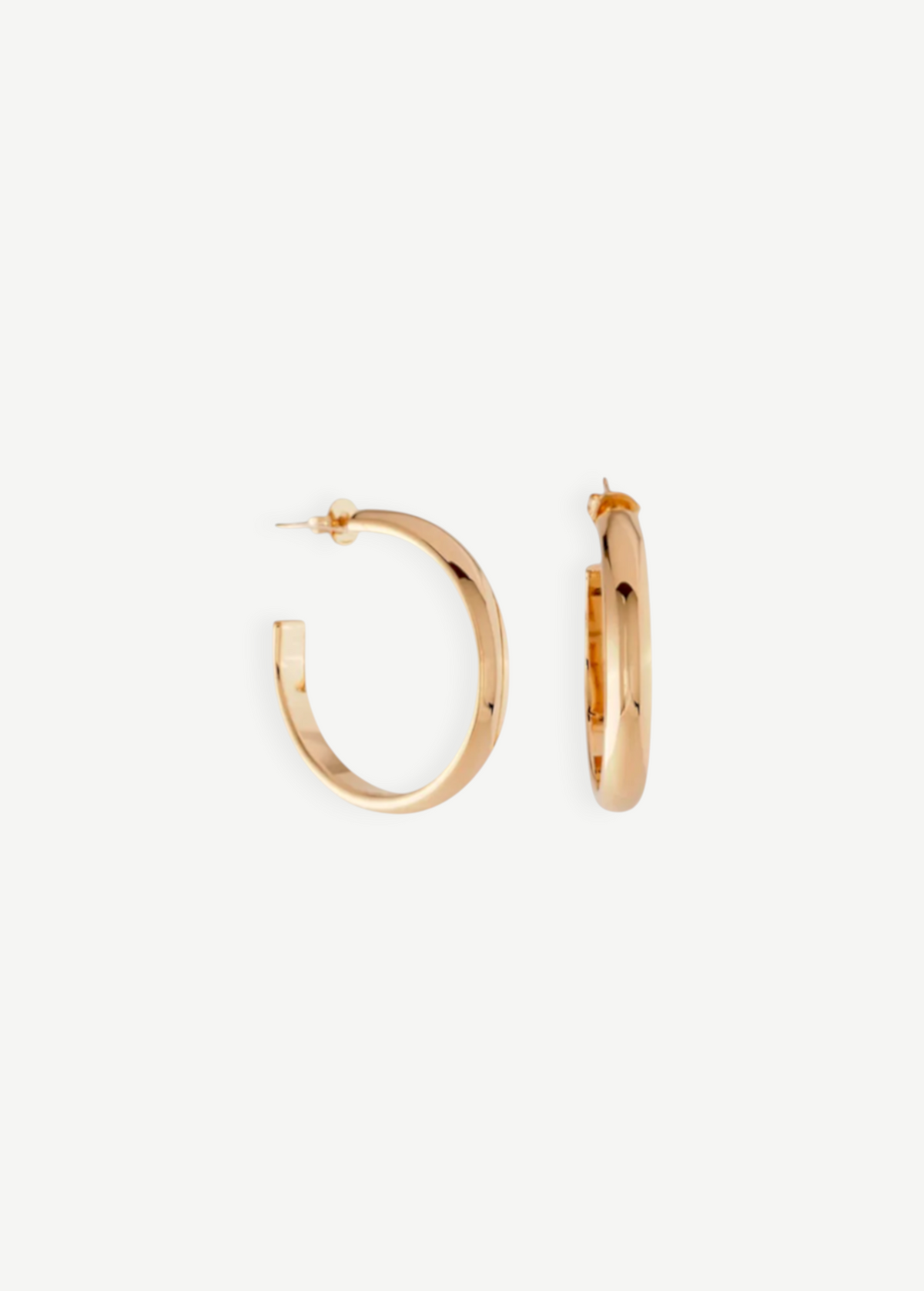 A pair of Irina Hoops 1.25″ featuring a shiny 14kt gold plate are displayed against a white background, with one earring shown front-facing and the other from the side to highlight their classic pierced back design.