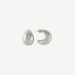 A pair of Jordyn Hoops in Rhodium—shiny, crescent-shaped stud earrings with pierced backs—are displayed against a plain white background, with one earring showing the front view and the other displaying the side profile.