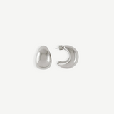 A pair of Jordyn Hoops in Rhodium—shiny, crescent-shaped stud earrings with pierced backs—are displayed against a plain white background, with one earring showing the front view and the other displaying the side profile.