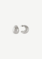 A pair of Jordyn Hoops in Rhodium—shiny, crescent-shaped stud earrings with pierced backs—are displayed against a plain white background, with one earring showing the front view and the other displaying the side profile.