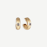 The Kaia Earrings are a pair of small, chunky gold plated hoops, each featuring a single round white gemstone accented with subtle crystal detailing, shown against a plain white background.