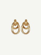 The Ami Earrings are a pair of pierced back earrings, each showcasing three interlocking circular loops, beautifully crafted in 14KT gold plate with an elegant 1.5-inch drop, shown against a plain white background.