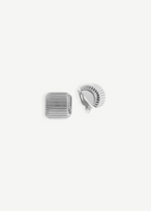 Presenting the Elle Earrings: a pair of silver, square-shaped clip-on earrings featuring grooved, ridged surfaces and a luxurious 14KT gold plate accent. One earring is displayed from the front and the other from the back to highlight the secure clip mechanism, all set against a plain white background.