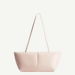 The Boulevard Sling Bag is a light pink, minimalist padded handbag featuring two symmetrical panels and thin straps, displayed on a plain white background.