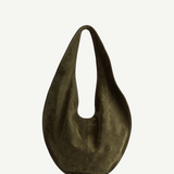 The Market Tote Bag is a dark olive green, crescent-shaped suede bag featuring a single wide strap, shown against a plain white background.