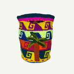 Introducing the Palmeras Bag Sac: a vibrant, handwoven basket bag adorned with geometric patterns and a distinctive palm tree motif on the front. Featuring bold stripes in yellow, green, purple, pink, and blue, this colorful handmade bag is both eye-catching and practical.