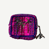 The Pochette Feliz Palmiers Fond Bag is a small, rectangular, handmade woven pouch in bright pink and purple featuring two black embroidered palm trees and finished with a zipper topped by a tassel.