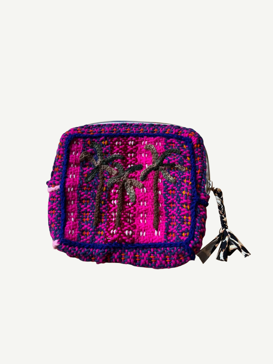 The Pochette Feliz Palmiers Fond Bag is a small, rectangular, handmade woven pouch in bright pink and purple featuring two black embroidered palm trees and finished with a zipper topped by a tassel.