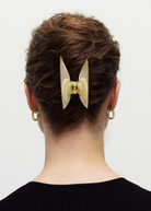 KABE SHOP INC Midi Heirloom hair claw in cream Italian acetate worn in a bun on a woman with gold hoop earrings