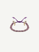 Introducing the N° 183 Braided Bracelet: this adjustable, handcrafted piece features purple and gold braiding with elegant gold chain tassels at each end. Shown against a white backdrop, it’s a versatile accessory—ideal for daily wear or as a thoughtful gift.