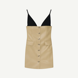 The Zyana Dress is a sleeveless mini with a bold fabric-blocked design, pairing a deep black V-neck bodice and thin black straps with a beige faux leather buttoned skirt and front pockets for a flattering mini silhouette.