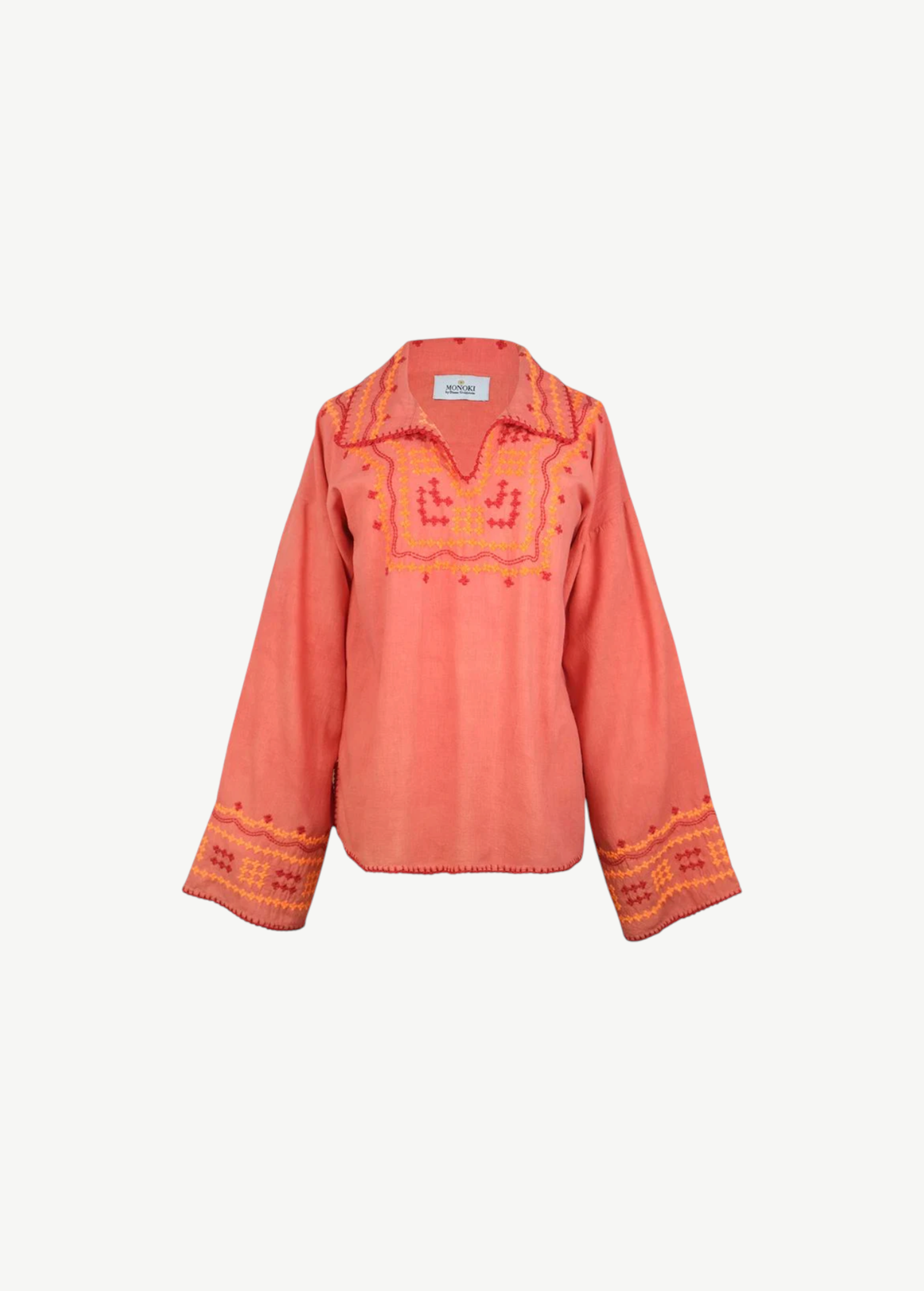 The Poppy Shirt is a long-sleeve, coral-colored silk blouse adorned with yellow and pink embroidered patterns on the chest, cuffs, and collar. This elegant embroidered shirt features slightly flared sleeves and a split neckline. For best care, it is dry clean only.