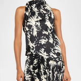 Woman wearing the Light Weight Drill Cowl Neck Top and a matching pleated skirt in black and white abstract print satin twill, accessorized with a metallic clutch and gold earrings—a statement look reminiscent of Marques’Almeida’s bold aesthetic.