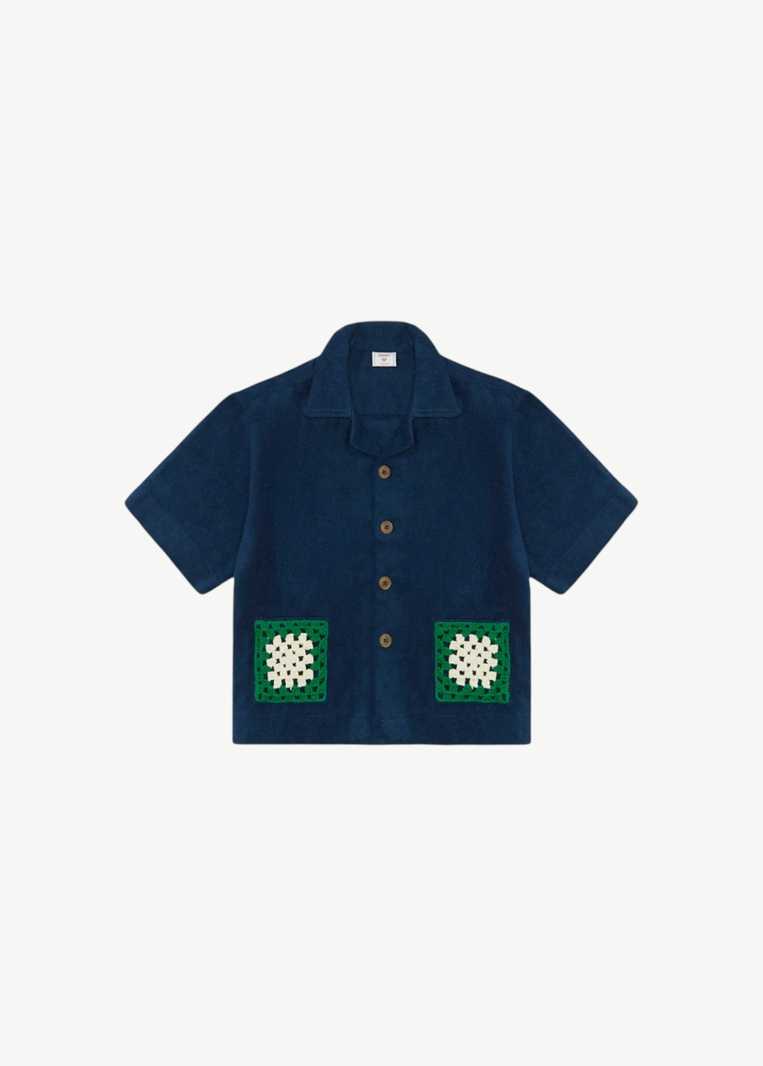 Boxy Shirt Crochet: an oversized navy button-down shirt in organic cotton with a notched collar and two square crochet pockets featuring white and green floral patterns.