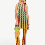A person wearing a sleeveless knit tunic and matching Ophelia Knit Pant in a colorful vertical chevron pattern, carrying a pineapple-shaped handbag.