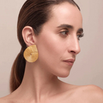 KABE SHOP INC Wixa earrings featuring a gold-toned, sculptural spiral design worn by a woman in profile.