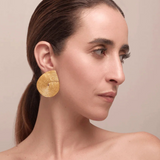 KABE SHOP INC Wixa earrings featuring a gold-toned, sculptural spiral design worn by a woman in profile.
