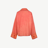 Back view of the Poppy Shirt, a coral pink embroidered jacket featuring wide sleeves, orange and yellow geometric embroidery on the cuffs, and matching trim along the edges. Dry clean only.