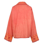 Back view of the Poppy Shirt, a coral pink embroidered jacket featuring wide sleeves, orange and yellow geometric embroidery on the cuffs, and matching trim along the edges. Dry clean only.