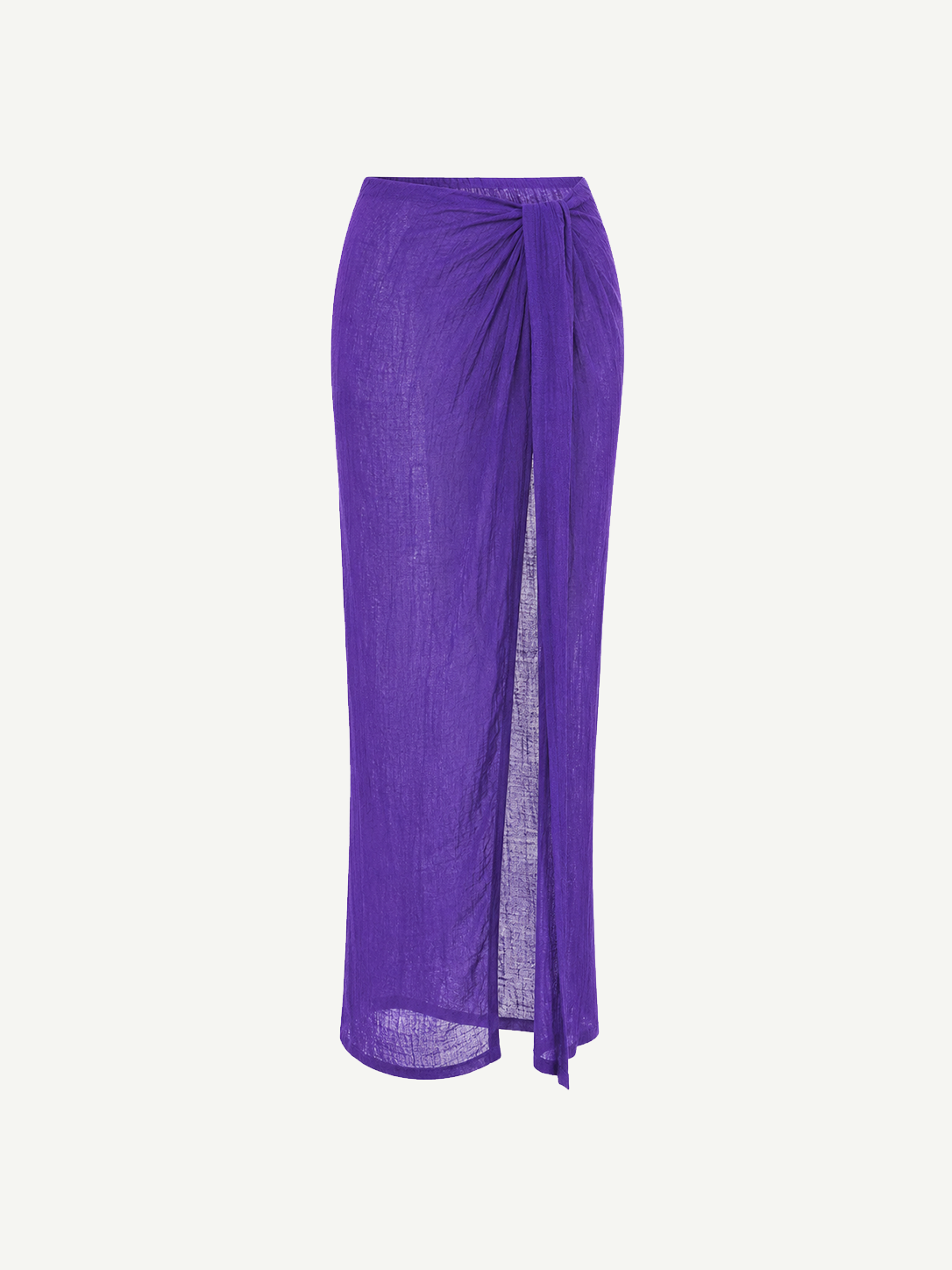 The Sarong Skirt is a long, sheer, pleated purple skirt featuring a side slit and a draped tie detail at the waist, shown against a plain white background.
