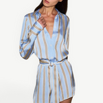 Model wearing a KABE SHOP INC Formentera romper in light blue with vertical tan stripes, collar, and tie-waist.