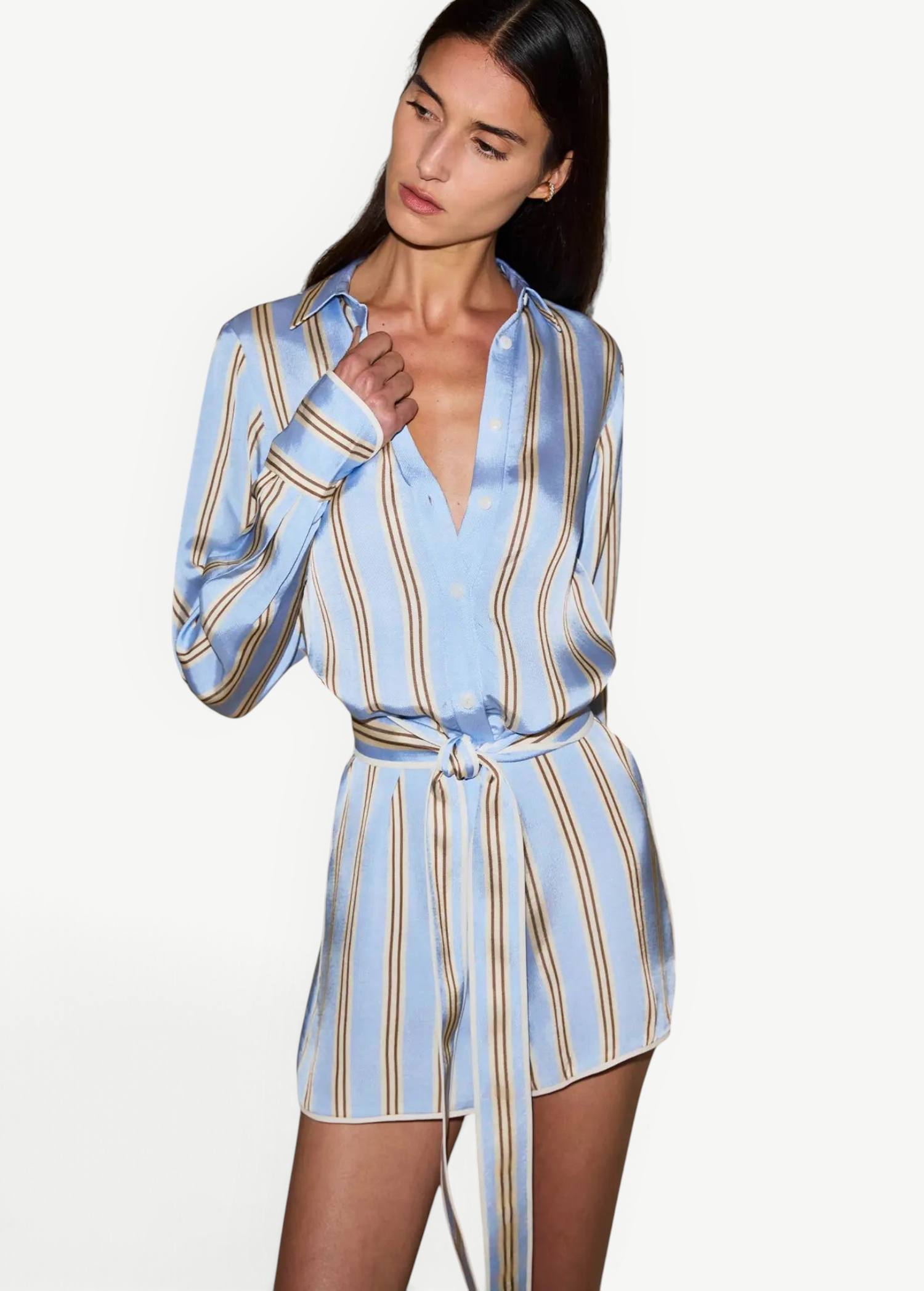 Model wearing a KABE SHOP INC Formentera romper in light blue with vertical tan stripes, collar, and tie-waist.