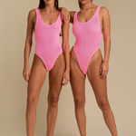 Two models wearing KABE SHOP INC Ruby one-piece swimsuits in bright pink with a textured fabric and high-cut design.