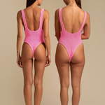 Two women wearing KABE SHOP INC pink textured one-piece swimsuits with a high-cut leg and low back design.