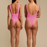 Two women wearing KABE SHOP INC pink textured one-piece swimsuits with a high-cut leg and low back design.